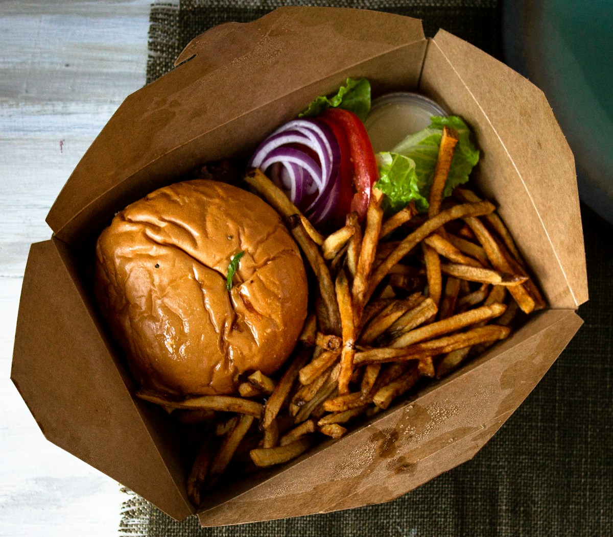 Burger and golden chips in a takeaway box